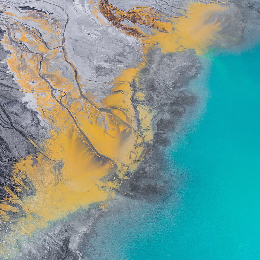 Aerial view of yellow sediment flowing into turquoise ocean water
