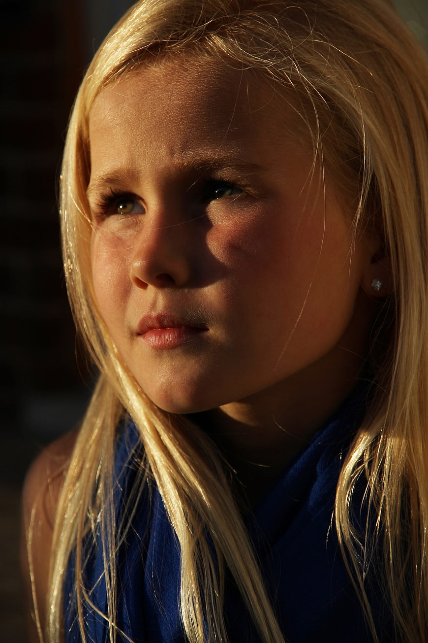 Close-up portrait of a blonde girl in golden sunlight