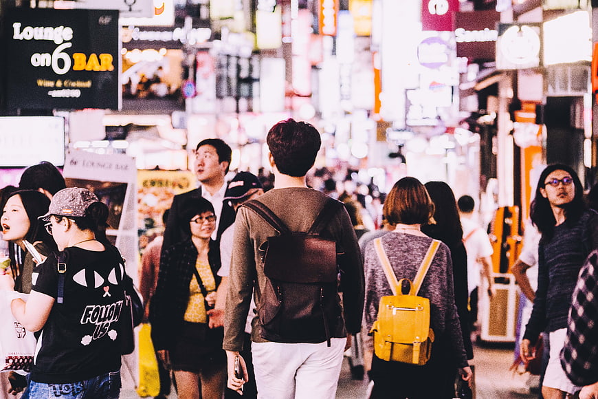 Crowd walking through neon-lit street at night in Seoul