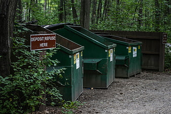 Green Dumpsters in Forest with Deposit Refuse Sign