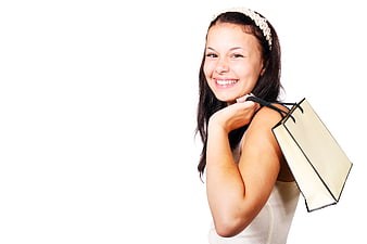 Happy young woman holding shopping bag on white background