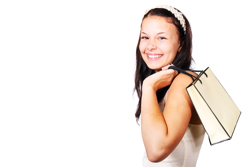 Happy young woman holding shopping bag on white background