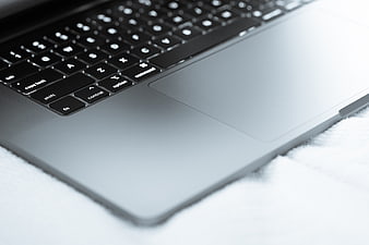 Close-up of laptop keyboard and trackpad on white surface