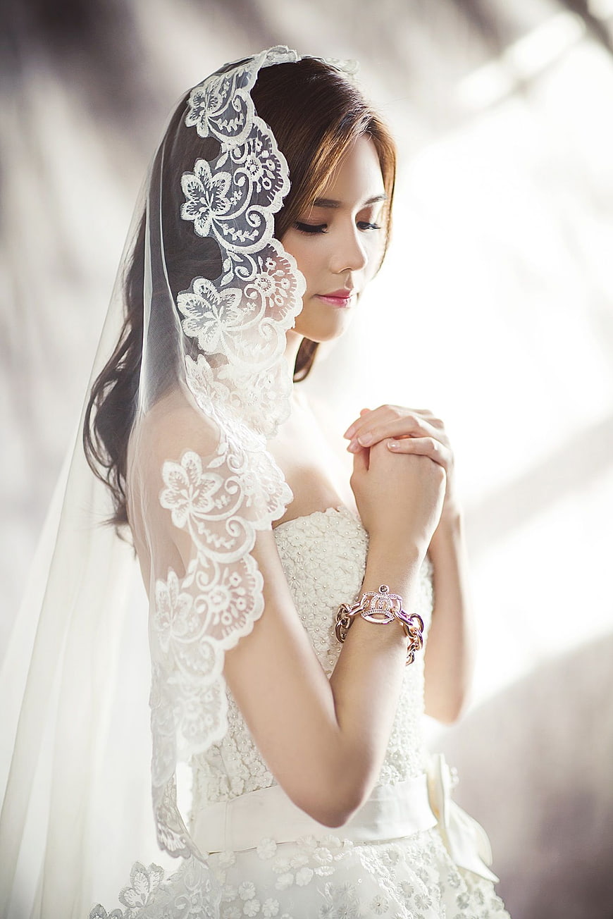 Bride in White Lace Veil Praying with Hands Clasped
