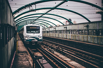 White Metro Train Arriving at Urban Station with Green Arches