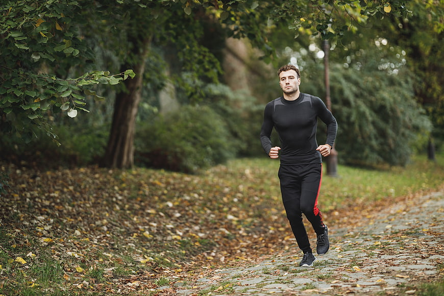 Athletic Man Running on Cobblestone Path in Autumn Park