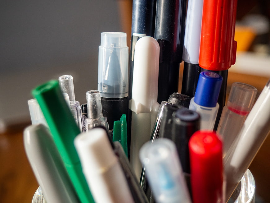 Close-up of colorful pens and markers in a glass holder