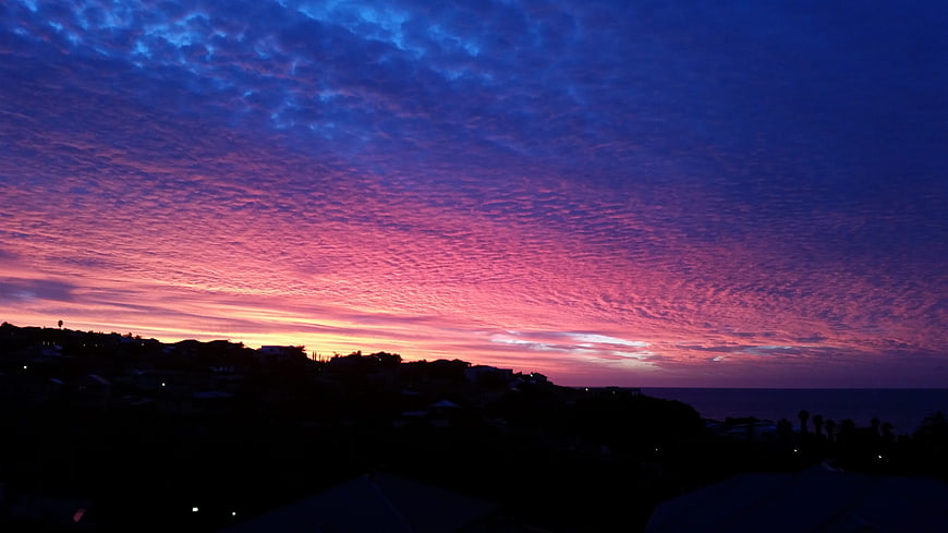Vibrant purple and pink sunset sky over coastal silhouette