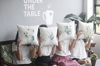 Four girls holding cactus pillows on a sofa