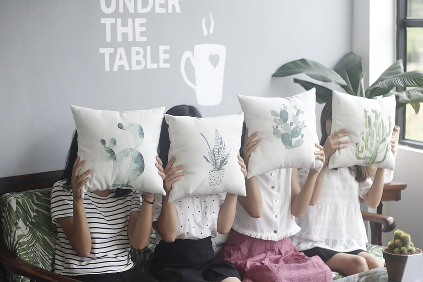 Four girls holding cactus pillows on a sofa