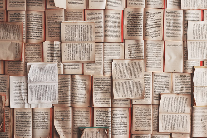 Vintage open books pinned to wall background texture