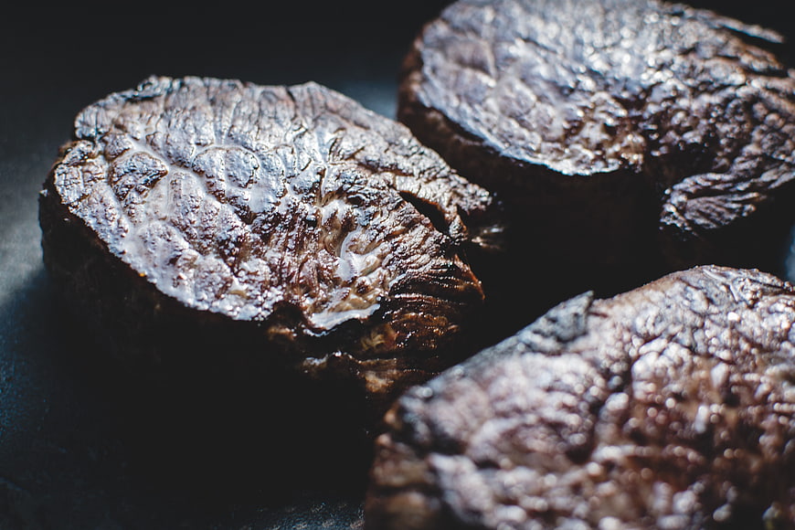Close-up of seared beef steaks on dark background