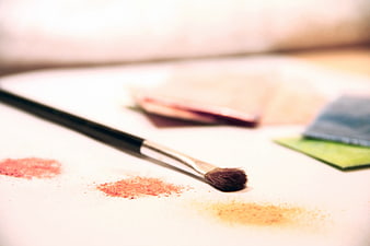 Makeup Brush with Loose Pigment on White Surface
