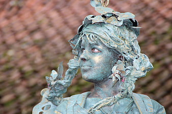Close-up of weathered bronze statue of a girl with leaf crown