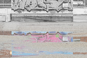 Colorful graffiti reflection in puddle against black and white wall