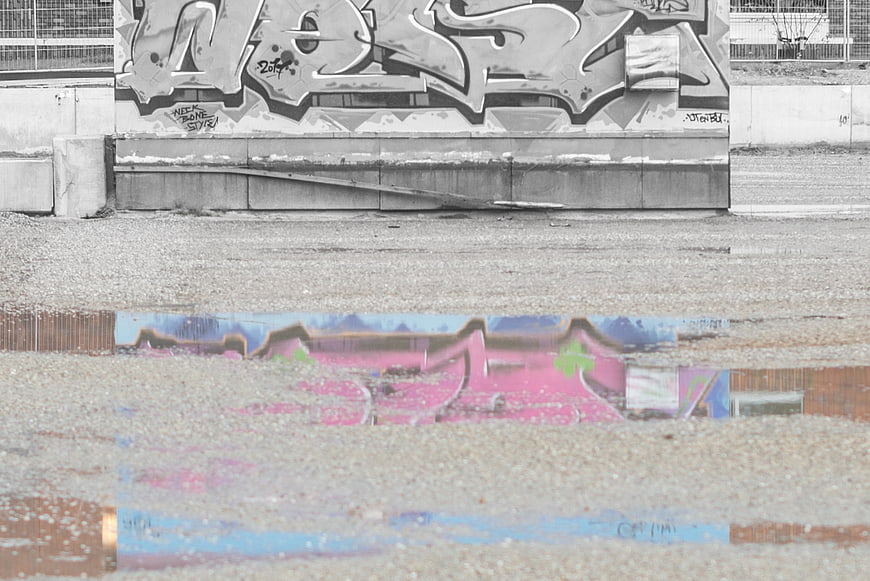Colorful graffiti reflection in puddle against black and white wall