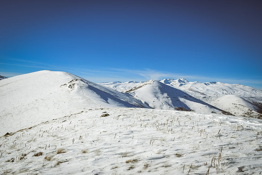 Snow-covered mountain landscape with blue sky and dry grass