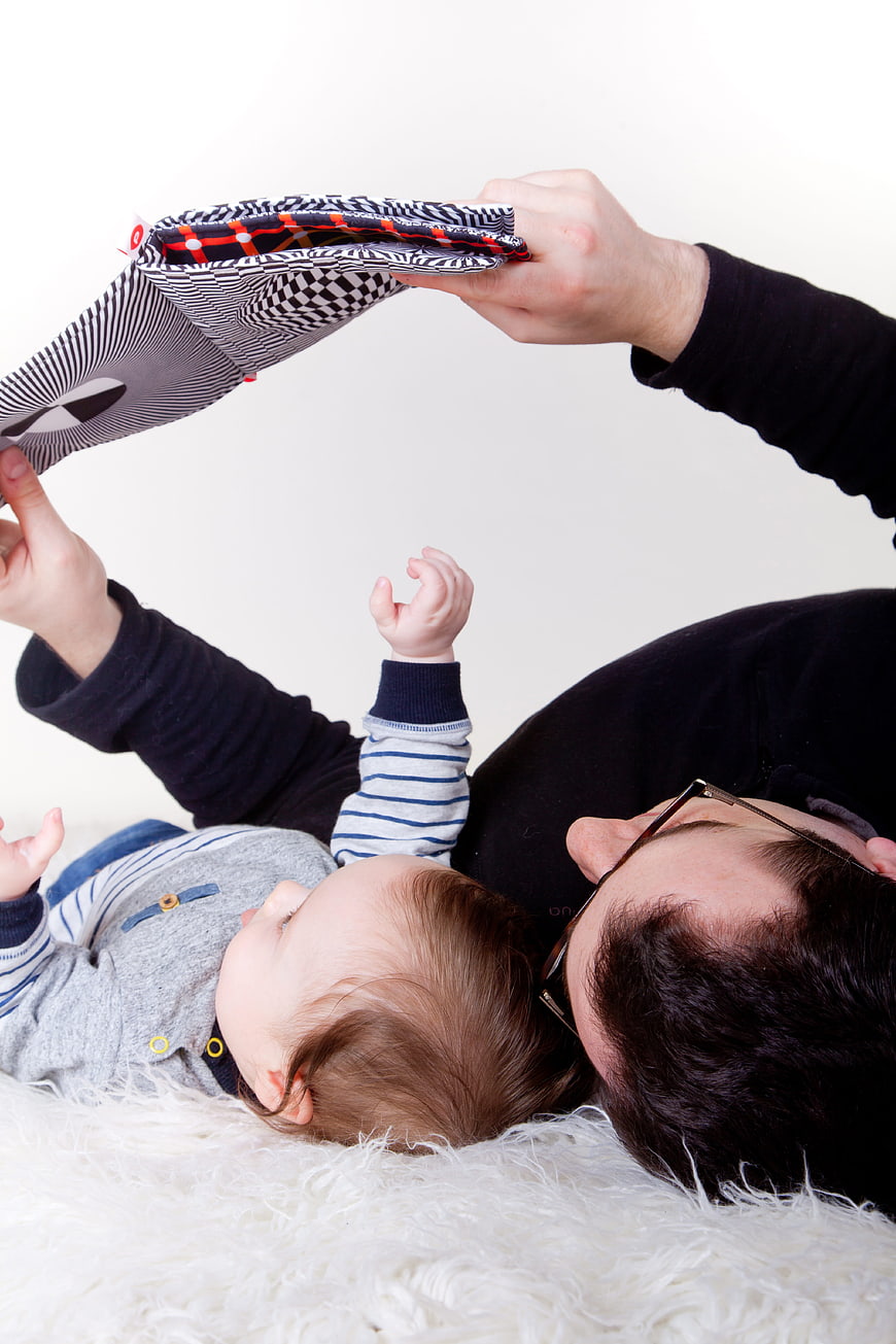 Father and baby playing with book on white rug