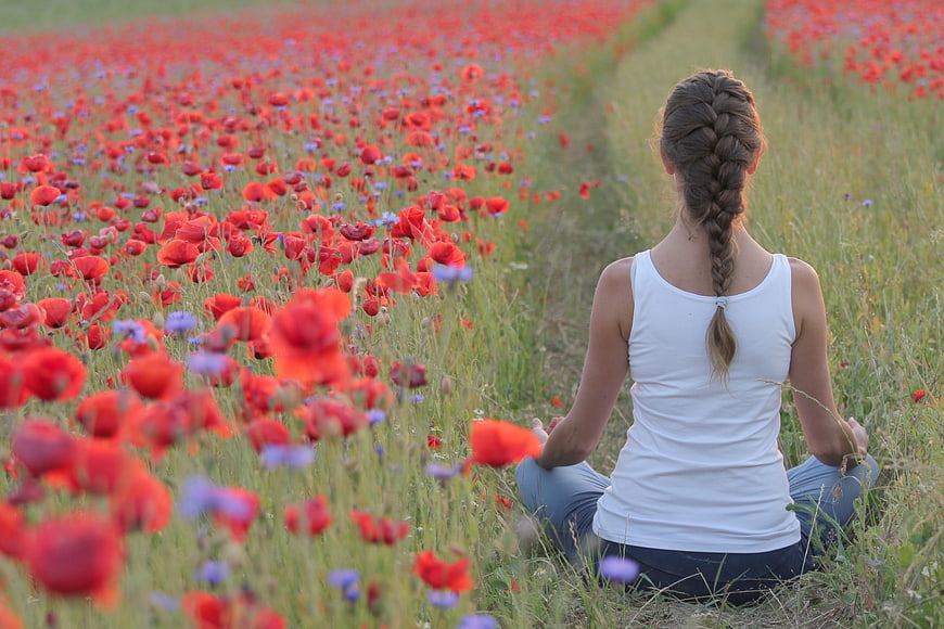 Woman meditating in a field of red poppies
