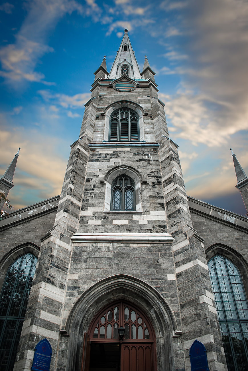Low angle view of historic stone church tower against blue sky