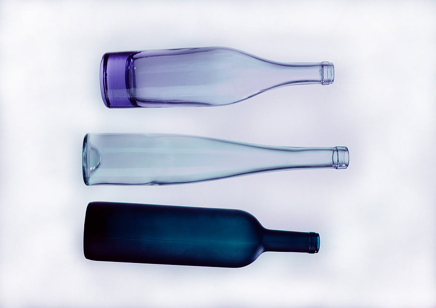 Three Glass Bottles in Blue and Purple Tones on White Background