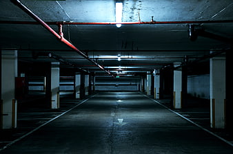 Empty Underground Parking Garage With Red Pipes And Concrete Pillars