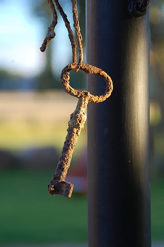 Rusty Antique Key Hanging on Black Metal Pole