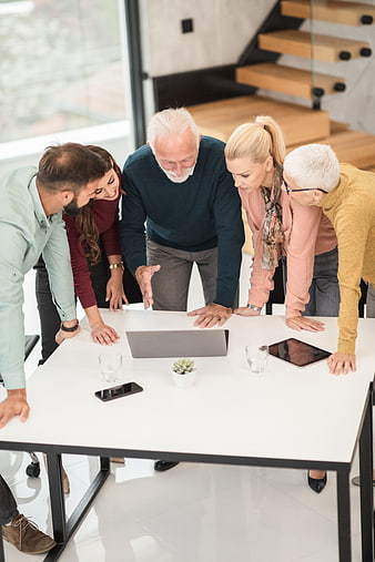 Multi-generational team collaborating around a laptop in modern office