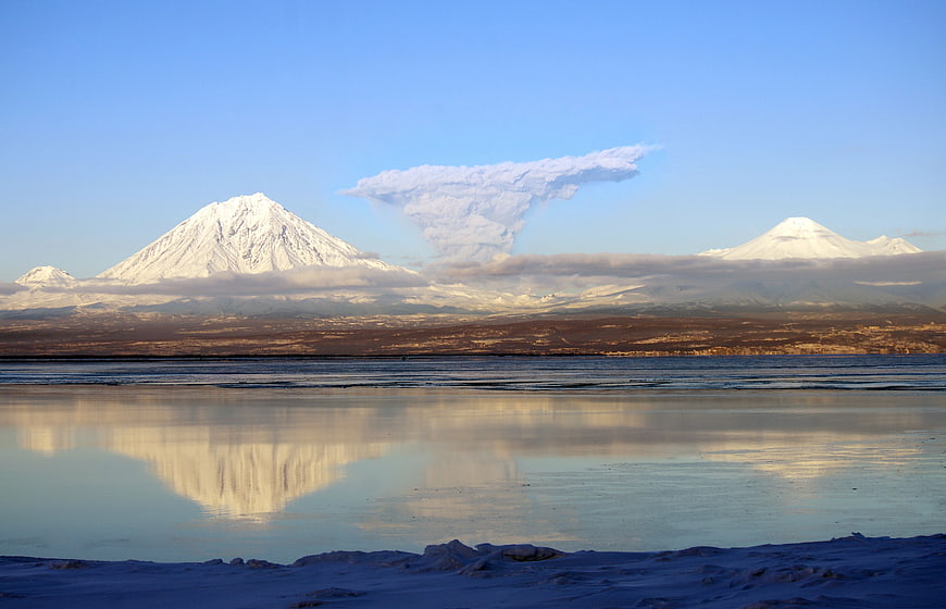 Snowy Mountain Peaks Reflected in Frozen Lake with Cloud