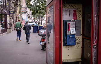 Red vintage phone booth on busy city street
