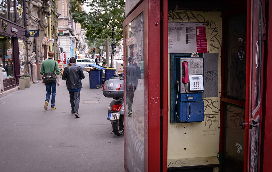 Red vintage phone booth on busy city street