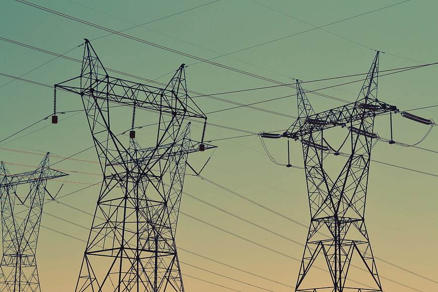 Silhouette of electricity pylons against gradient sky