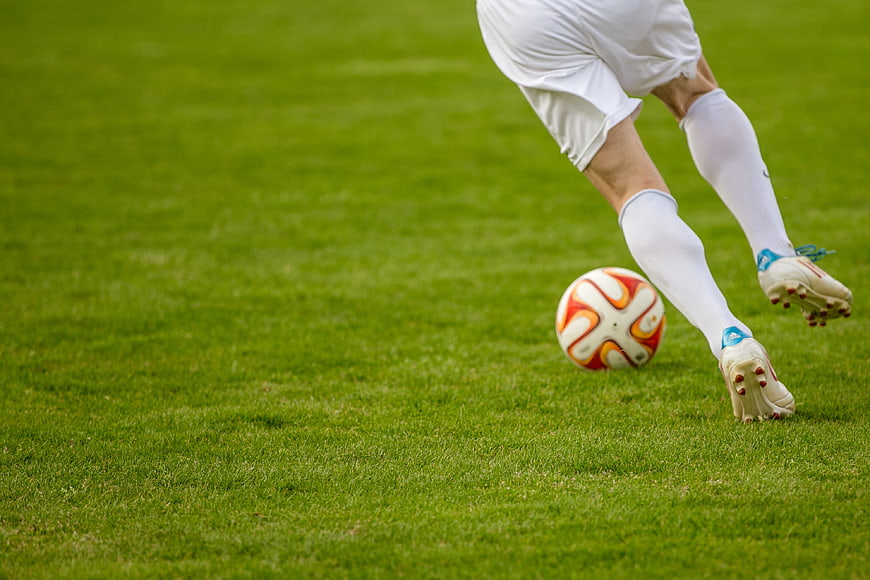 Soccer player kicking ball on green grass field