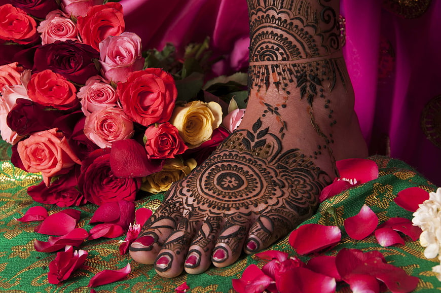 Close-up of Indian bride's foot with intricate henna mehndi design and red roses