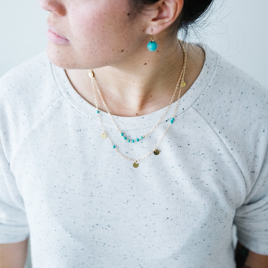 Woman Wearing Layered Gold and Turquoise Jewelry