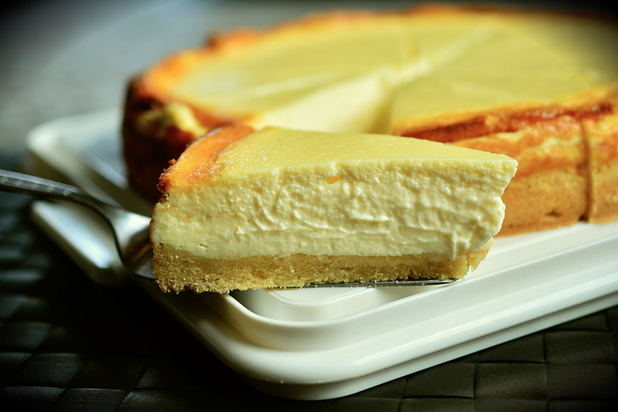 Slice of creamy cheesecake on a white plate with fork