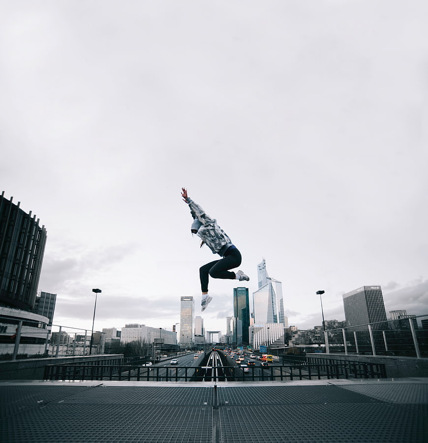 Woman jumping high in urban cityscape with skyscrapers