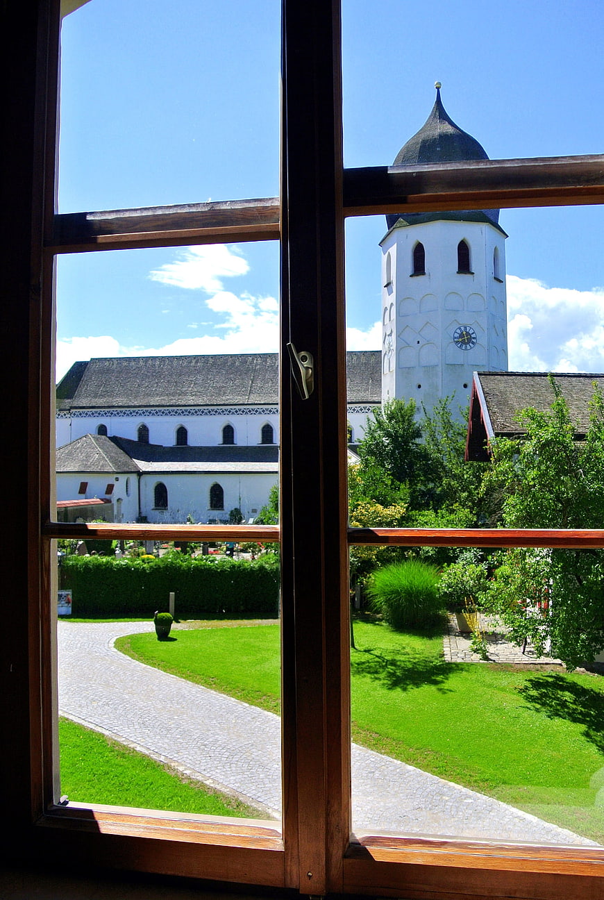 View of white church tower through wooden window frame