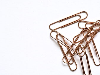 Copper paper clips on white background with copyspace
