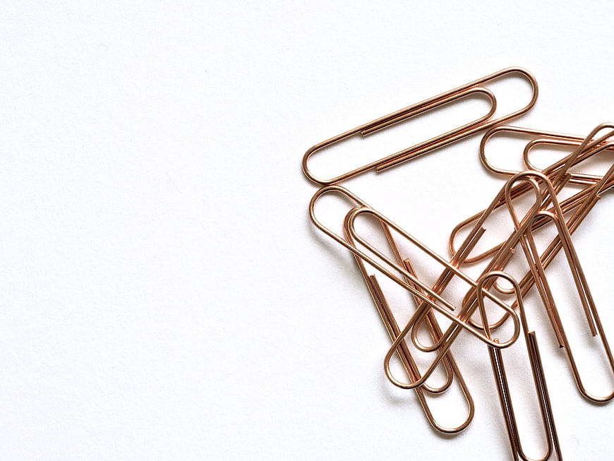 Copper paper clips on white background with copyspace