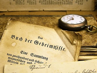 Antique pocket watch resting on open book of secrets