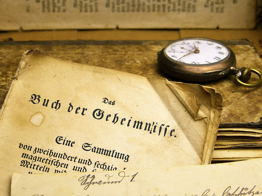 Antique pocket watch resting on open book of secrets