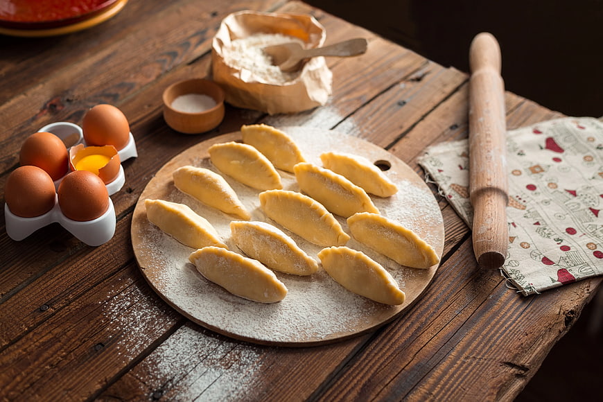 Homemade dumplings on wooden board with flour and eggs
