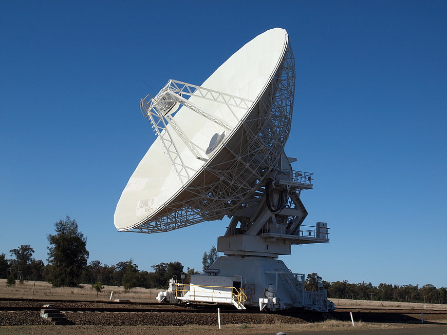 Large white radio telescope dish against clear blue sky