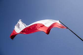Polish flag fluttering in the wind against a clear blue sky