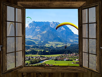Paragliders Soaring Over Alpine Valley Viewed Through Open Wooden Window