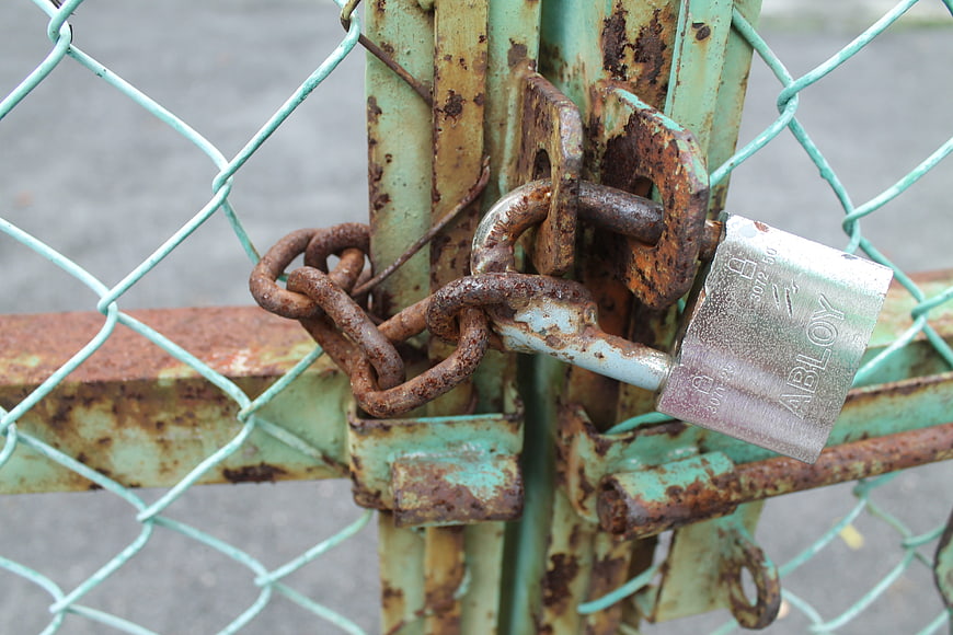 Rusty Chain and Padlock Securing a Weathered Green Metal Gate