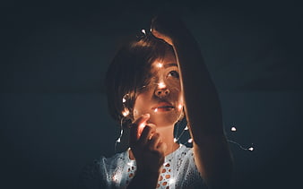 Woman with fairy lights in dark room