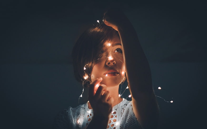Woman with fairy lights in dark room
