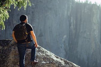 Hiker with Backpack Looking at Mountain Cliff View